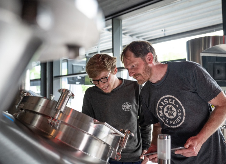 Azubi und Braumeister bei Maisel & Friends werfen gemeinsam einen Blick in den Sudkessel