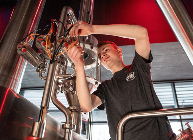Azubi bei Maisel & Friends prüft die Technik an der Brauanlage in der Brauerei