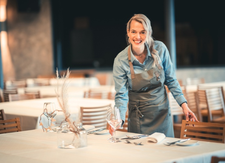 Freundliche Mitarbeiterin bei Maisel & Friends deckt einen Tisch im Restaurant ein – Ausbildung in Gastronomie und Service mit Herz