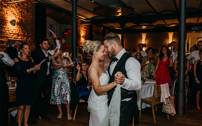 Brautpaar tanzt eng umarmt vor feiernden Gästen auf der Hochzeit