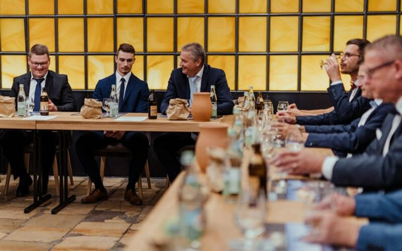 Geschäftsleute sitzen an einem Tisch und verkosten Getränke in einem Seminar