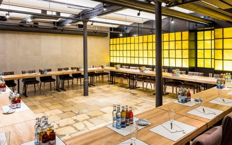 Großer Seminarraum mit U-förmiger Tischanordnung und vorbereiteten Arbeitsplätzen